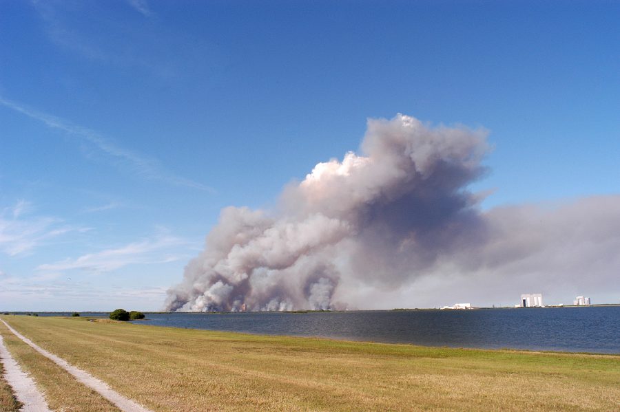 Fotomural KENNEDY SPACE CENTER, FLA. - A successful controlled burn near KSC’s Launch Complex 39 area creates clouds of smoke in a clear blue sky.  The water seen is the